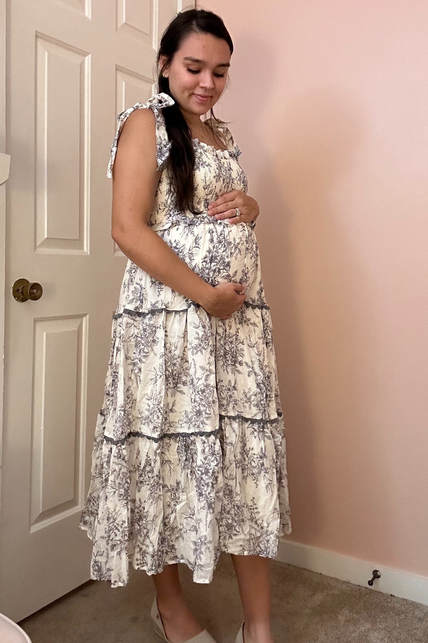 woman wearing a floral print maternity dress with ruffled tiers and holding her baby bump