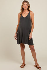 woman wearing a dark gray maternity dress with a V-neckline and flowy skirt, showcasing her baby bump