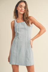 woman wearing a light blue denim mini dress with a square neckline and a fitted silhouette