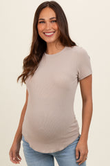 woman wearing a light beige short sleeve maternity top with a visible baby bump and styled with light blue jeans