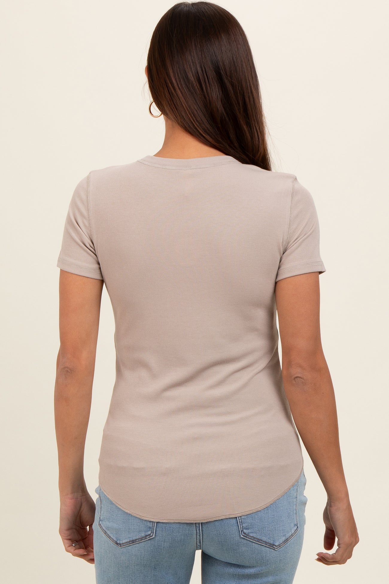 woman wearing a light brown ribbed short sleeve maternity top with a rounded hem and a relaxed fit