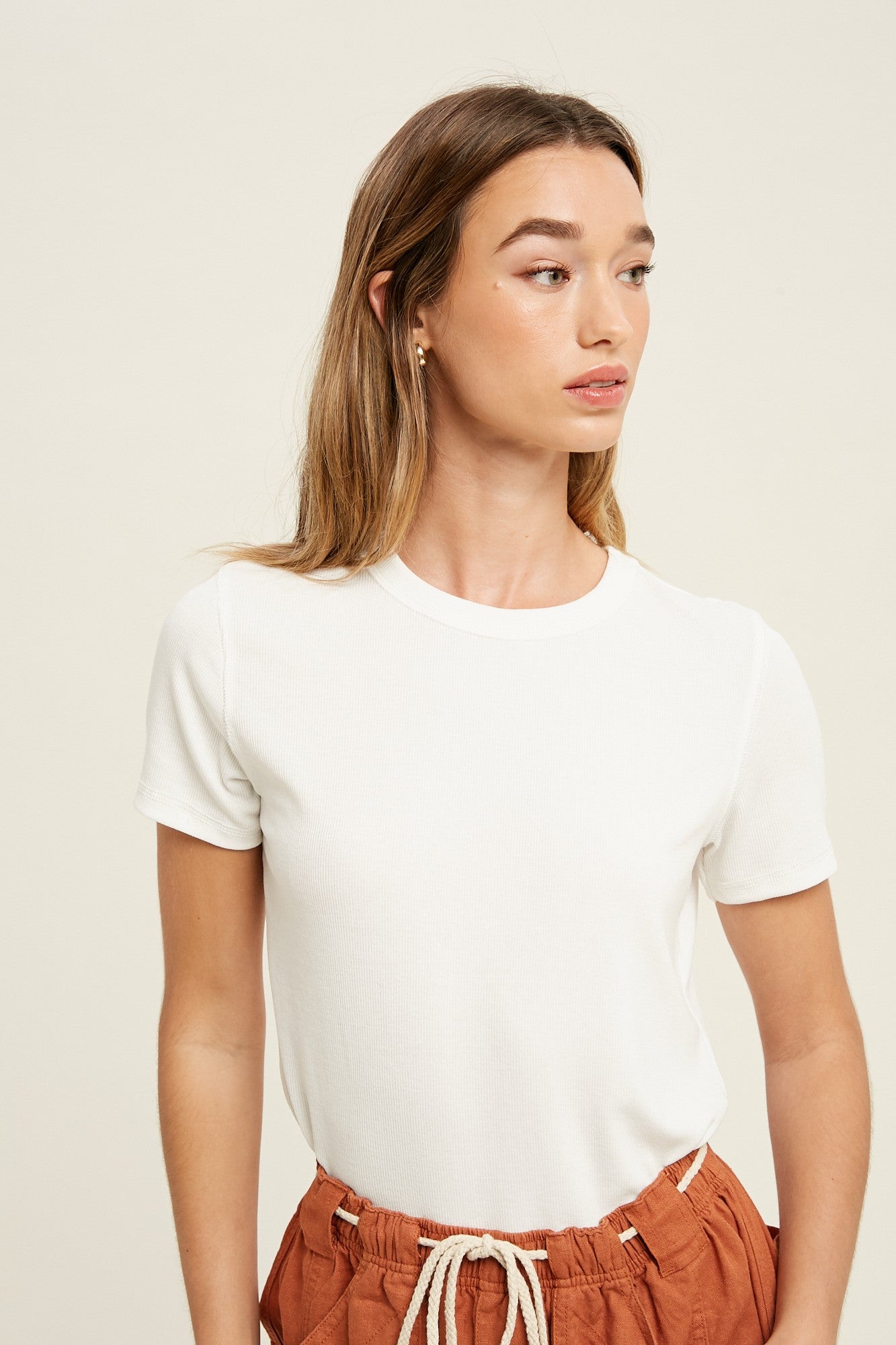 woman wearing a white short sleeve ribbed top paired with rust-colored drawstring trousers