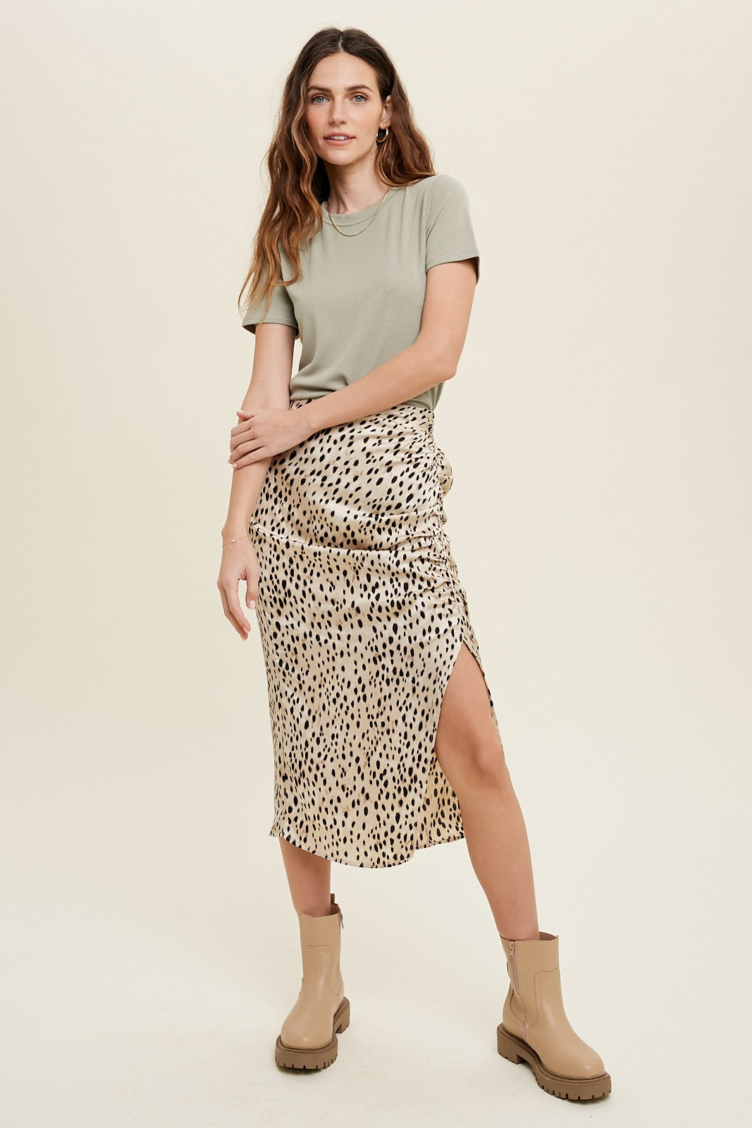 woman wearing a green short sleeve top and a leopard print midi skirt with a slit, paired with beige ankle boots