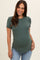 woman wearing a dark green short sleeve maternity top and showing her baby bump