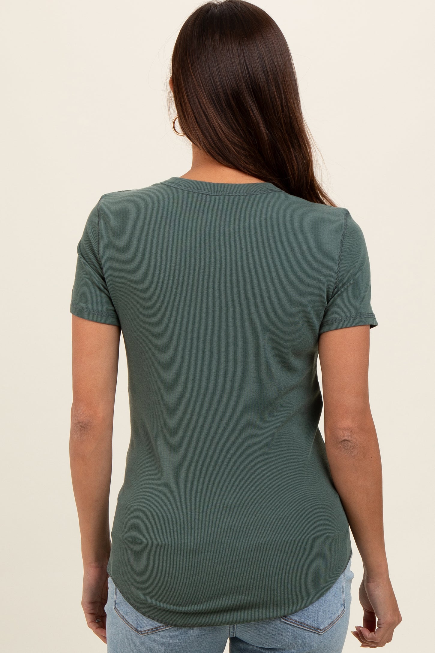 woman wearing a dark green short sleeve maternity top, shown from the back with a curved hem