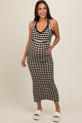 woman wearing a black and white houndstooth maternity maxi dress and smiling, showcasing her baby bump