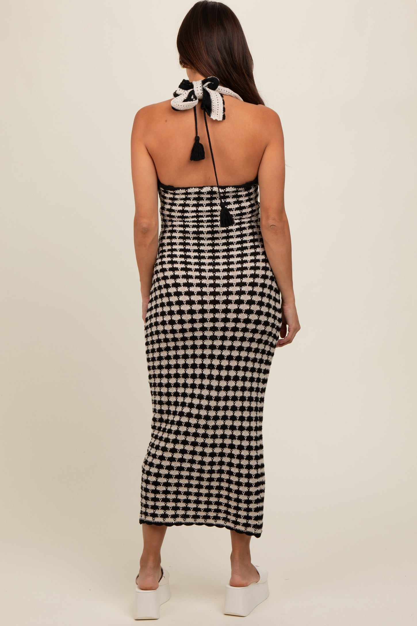 woman wearing a black and white checkered halter neck maternity dress with a tie at the back