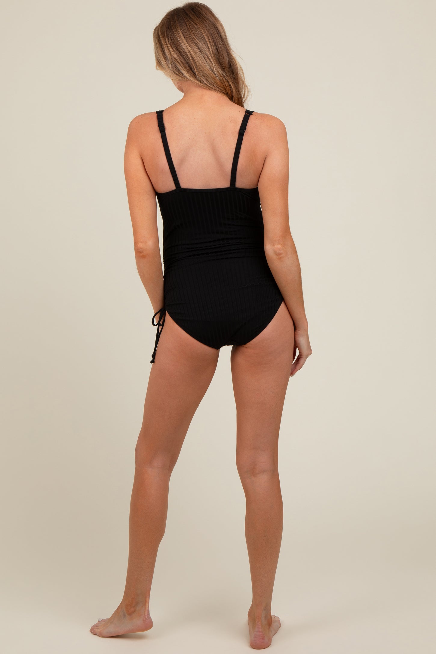 woman wearing a black maternity one-piece swimsuit with adjustable straps and ruched detailing on the back