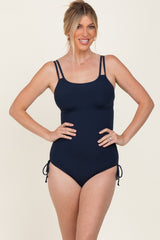 woman wearing a navy ribbed one-piece swimsuit with adjustable ties on the sides and double shoulder straps