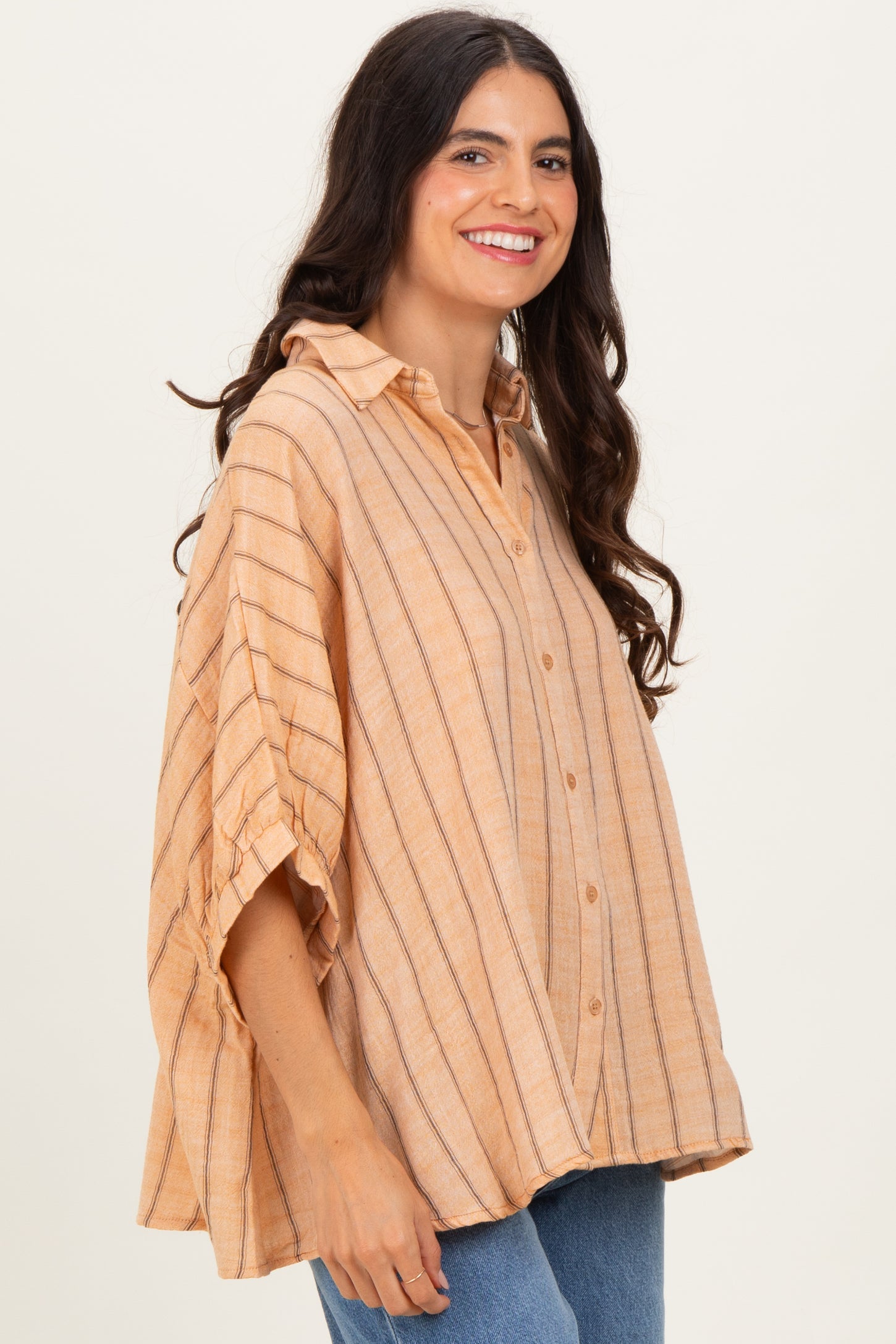 woman wearing a peach striped oversized button-up shirt with a collar and rolled sleeves