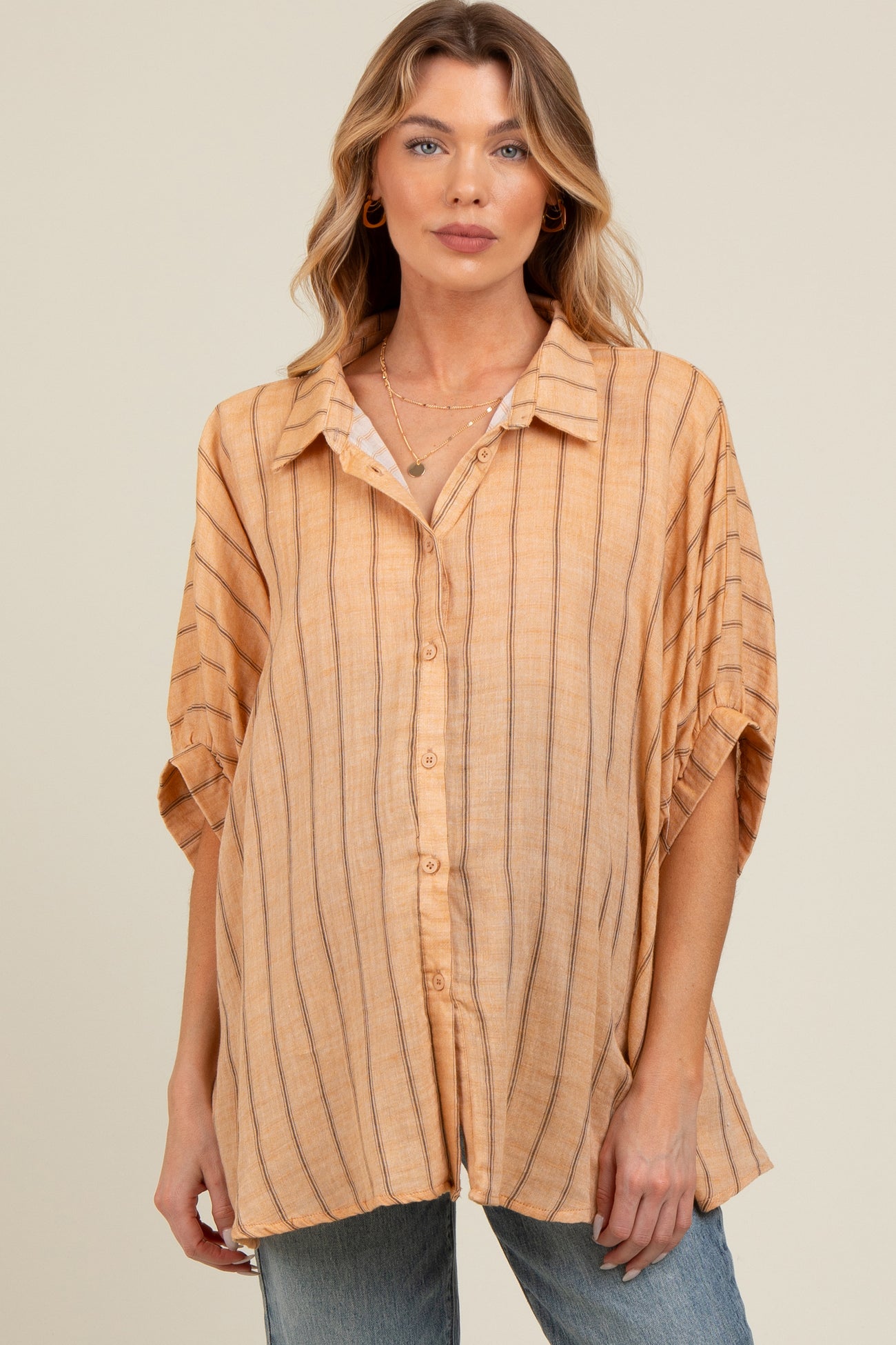 woman wearing a light orange striped maternity button-up shirt with short sleeves and relaxed fit