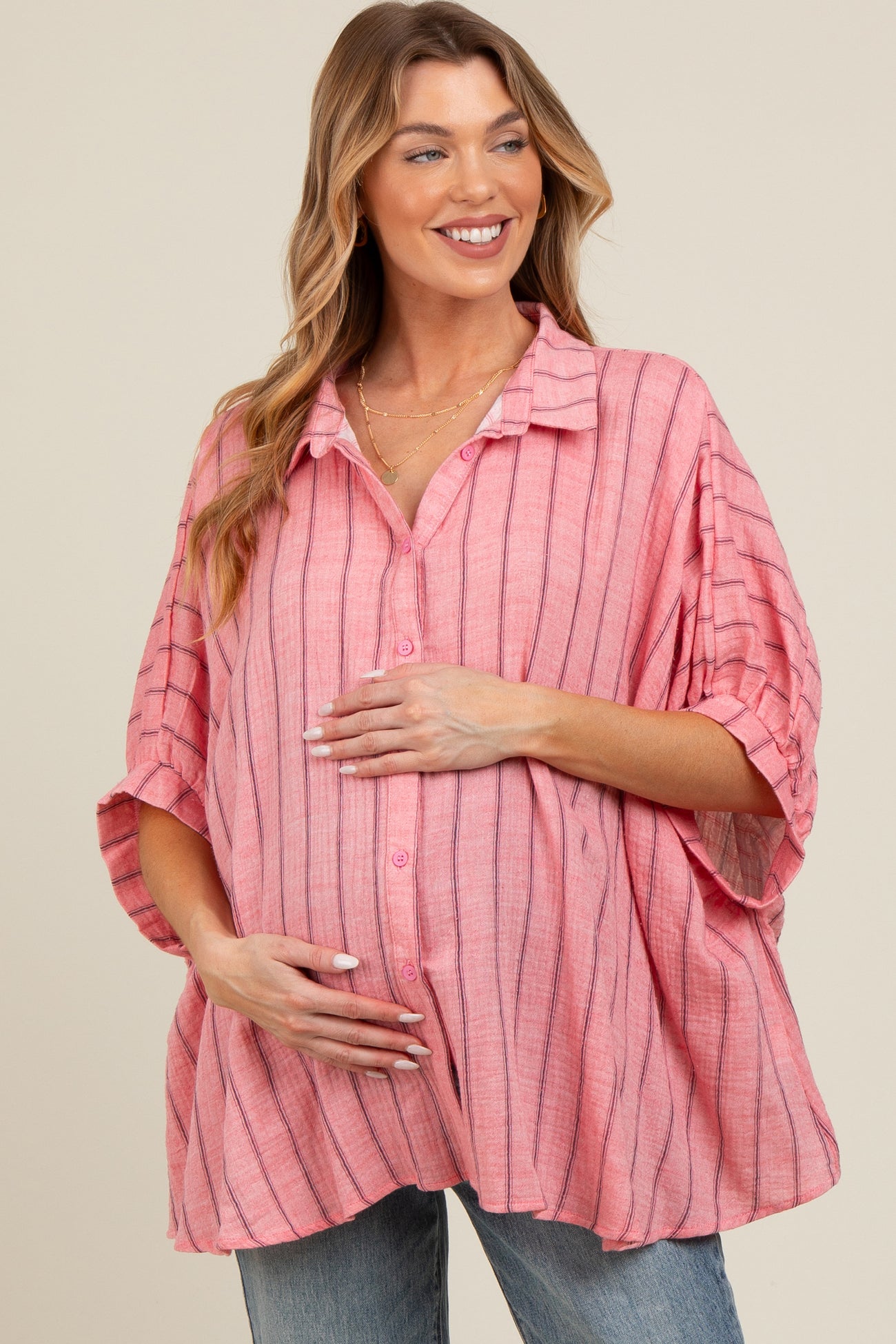 woman wearing a pink striped maternity shirt with a loose fit and holding her baby bump