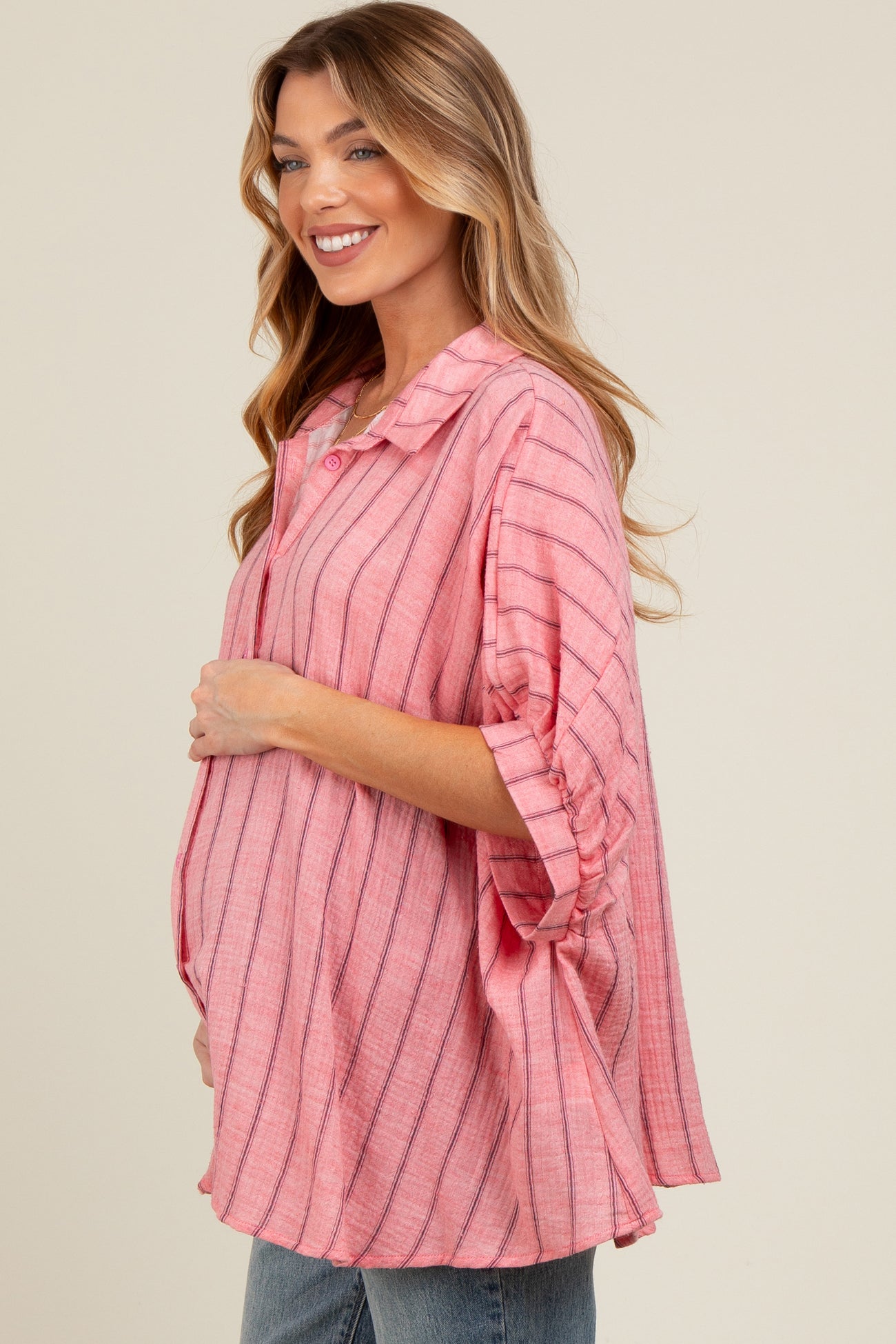 woman wearing a pink striped maternity top and holding her baby bump