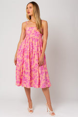 woman wearing a pink floral midi dress with spaghetti straps and a tiered skirt