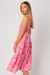 woman wearing a pink floral maxi dress with smocked bodice and tiered skirt, standing sideways to the camera