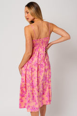 woman wearing a pink floral midi dress with a smocked bodice and adjustable straps, viewed from the back