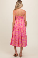 woman wearing a pink floral maternity dress with smocked bodice and tiered skirt, showcasing her baby bump from the back