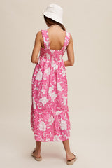 woman wearing a pink floral maxi dress with a smocked back and tiered hem, styled with a white bucket hat