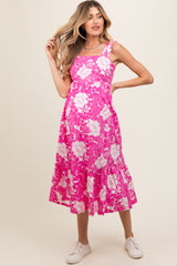 woman wearing a pink floral maternity dress with a flared hem and strappy design, showcasing her baby bump