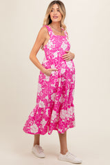 woman wearing a pink floral maternity dress with pockets and a visible baby bump