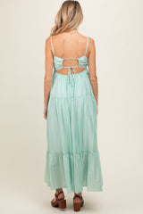 woman wearing a mint green backless maternity dress with adjustable spaghetti straps and a tiered skirt