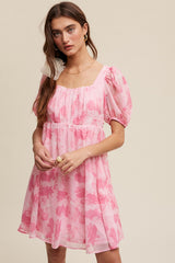 woman wearing a pink floral puff sleeve dress with a square neckline and gathered waist