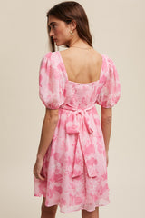 woman wearing a pink floral puff sleeve dress with a smocked back and tie detail