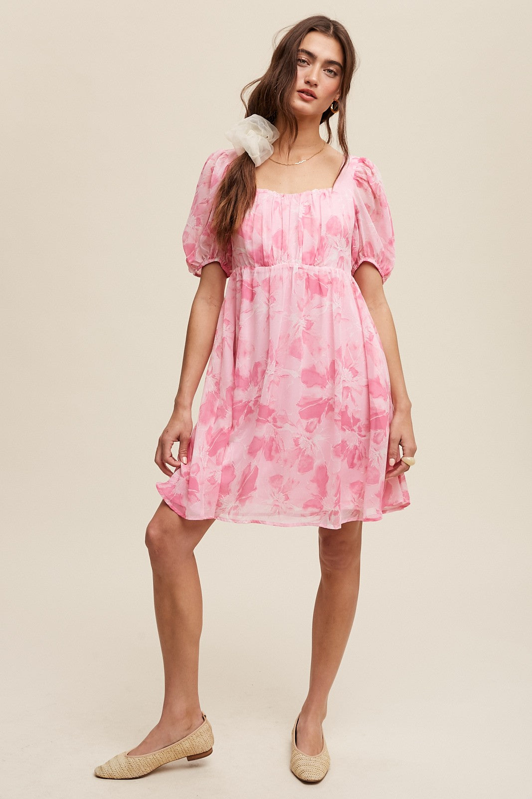 woman wearing a pink floral puff sleeve mini dress and beige espadrille flats