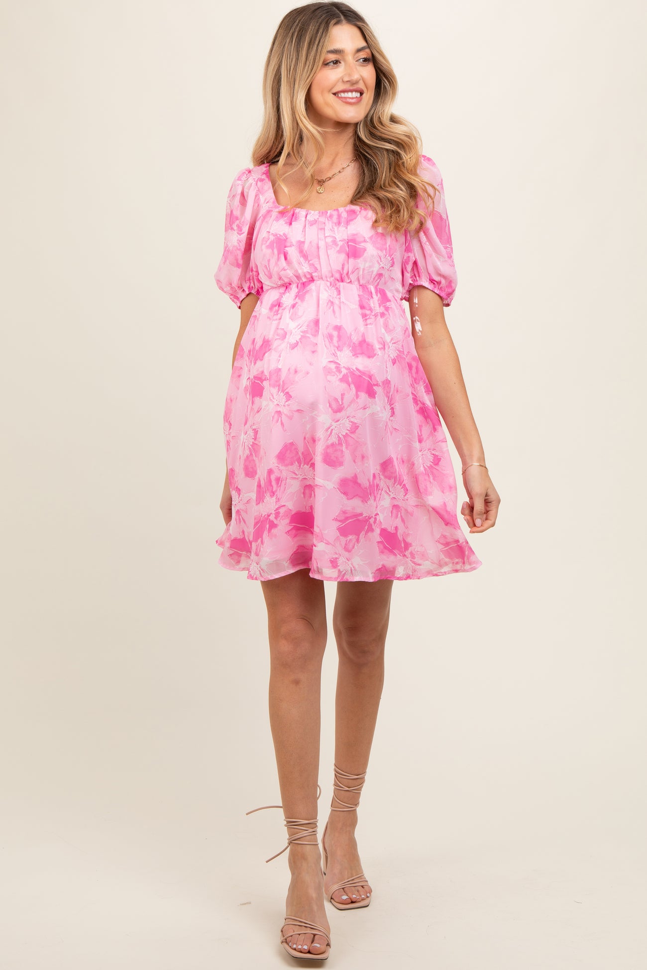 woman wearing a pink floral maternity dress with puff sleeves and a baby bump visible
