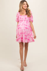 woman wearing a pink floral maternity dress with puff sleeves and a baby bump visible