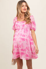 woman wearing a pink floral maternity dress with short puff sleeves and a fitted bodice, showing her baby bump