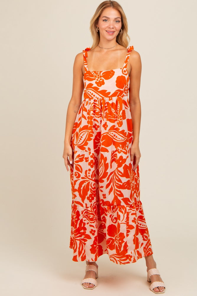 woman wearing a floral orange maxi dress with shoulder ties and a flared skirt
