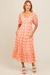 woman wearing a coral floral midi dress with puff sleeves and pockets, standing on a neutral background