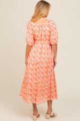 woman wearing a coral floral midi dress with puff sleeves and a smocked waist, shown from the back