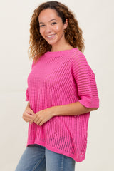 woman wearing a bright pink loose knit sweater with short sleeves and a relaxed fit styled with blue jeans