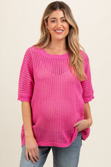 woman wearing a bright pink open knit maternity top with short sleeves and a visible baby bump