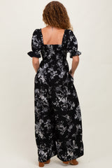 woman wearing a black floral print jumpsuit with short puff sleeves and a square back, showing the back view