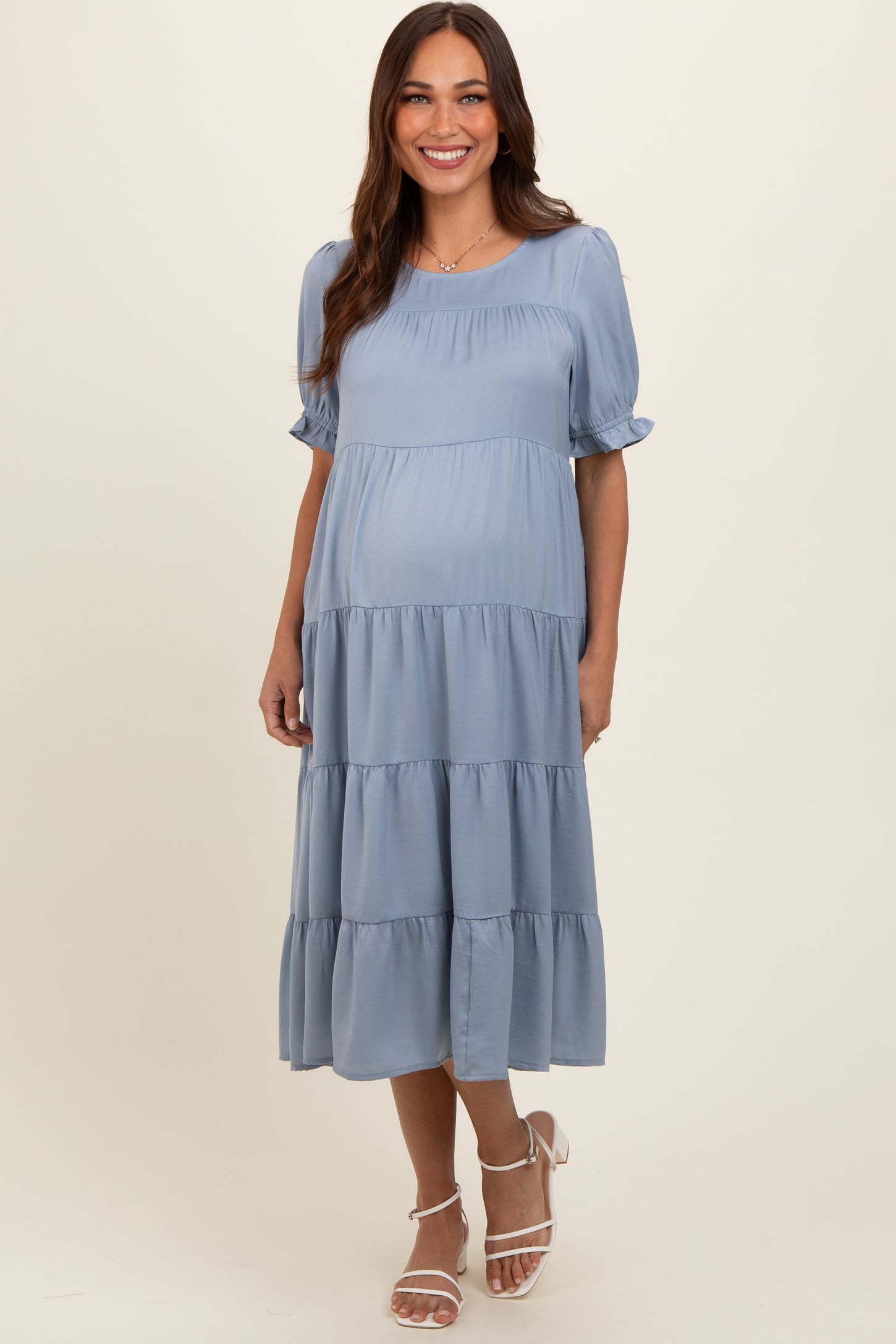 woman wearing a light blue maternity tiered midi dress with short puff sleeves and a baby bump visible