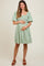 woman wearing a green floral maternity dress and holding her baby bump