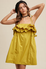 woman wearing a yellow ruffled mini dress with adjustable straps and a gathered waist