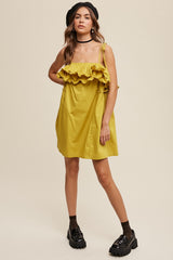 woman wearing a mustard yellow spaghetti strap dress with ruffle detailing and chunky black platform shoes