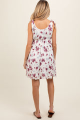 woman wearing a white floral maternity dress with adjustable tie straps and a loose fit, showing her baby bump from behind