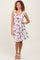 woman wearing a white floral summer dress with ruffled straps and a tie detail at the waist