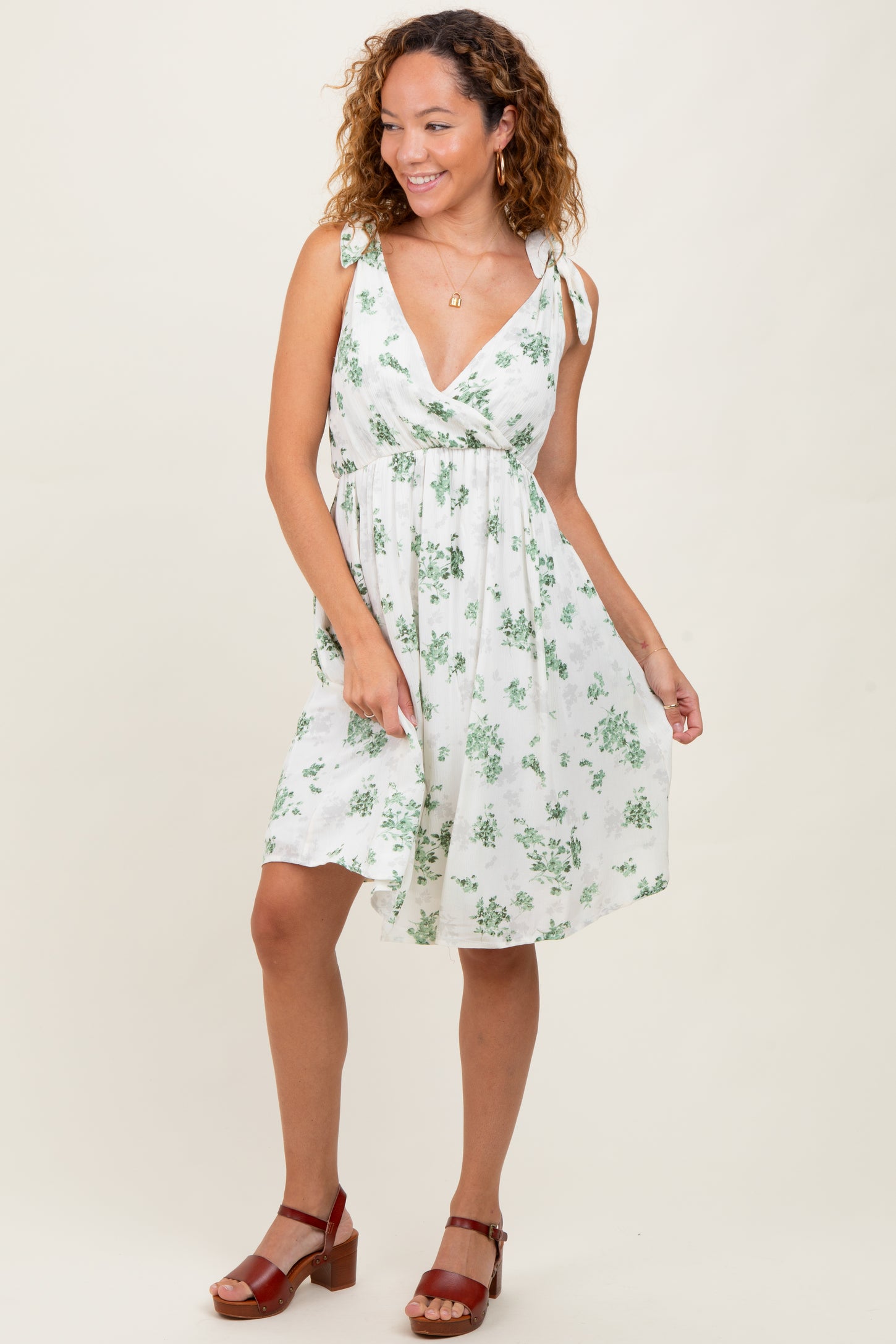 woman wearing a white floral print dress with tie straps and a flattering v-neckline