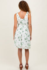woman wearing a white floral sundress with ties at the shoulders and a cinched waist, viewed from the back