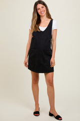 woman wearing a black denim maternity dress with pockets over a white top and posing casually