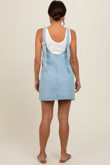 woman wearing a light blue denim maternity dress with adjustable straps, viewed from the back