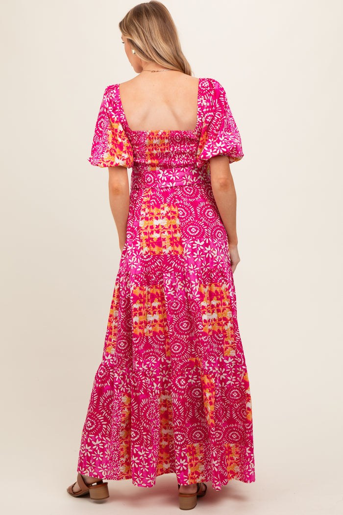 woman wearing a pink floral maternity maxi dress with puff sleeves and a smocked back design