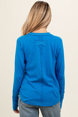 woman wearing a vibrant blue long sleeve maternity top, showing the back view with a simple design detail