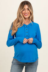 woman wearing a blue long sleeve maternity top with button details and a visible baby bump